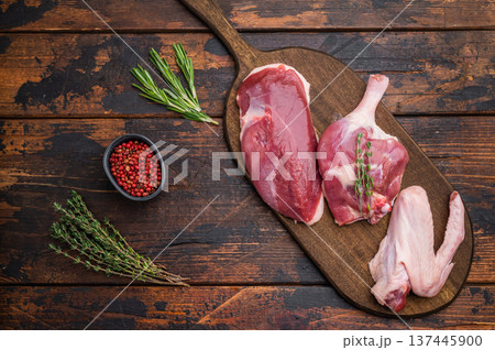 Plucked raw duck meat selection displayed on rustic board with seasoning against dark wood backdrop showcasing premium poultry. Plucked raw duck meat selection displayed on rustic board with seasoning against dark wood backdrop showcasing premium poultry. 137445900