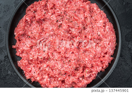 Fresh raw ground mince beef and pork meat with seasoning on black plate over dark textured background ideal for cooking, butcher and protein ingredient themes. Fresh raw ground mince beef and pork meat with seasoning on black plate over dark textured background ideal for cooking, butcher and protein ingredient themes. 137445901