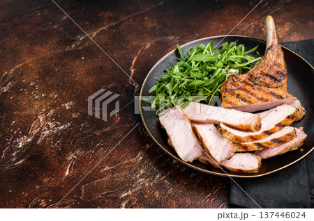 Succulent grilled Tomahawk pork chop, rib bone in steak featuring crispy edges and juicy meat that will tantalize your taste buds. brown background. top view 137446024