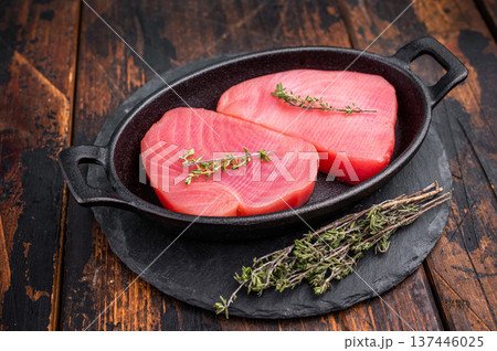 Vibrant raw tuna steak, showcasing its deep red hue, an essential ingredient for sushi enthusiasts and seafood connoisseurs. wooden background. top view Vibrant raw tuna steak, showcasing its deep red hue, an essential ingredient for sushi enthusiasts and seafood connoisseurs. wooden background. top view 137446025