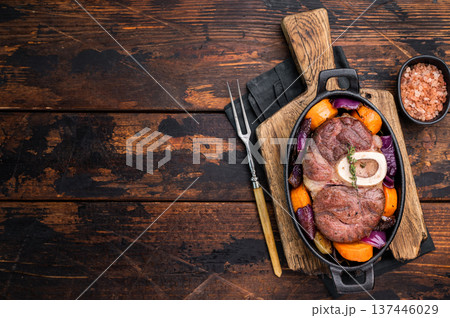 Hearty ossobuco slow cooked to perfection, showcasing succulent osso buco shank meat and aromatic herbs in a comforting stew. wooden background. top view 137446029
