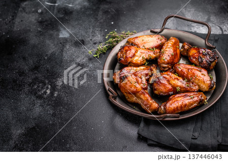 Savory grilled chicken wings smothered in tangy barbecue sauce, the ultimate treat for meat lovers and party enthusiasts. black background. top view 137446043