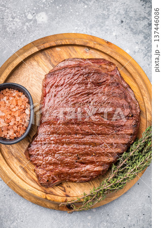 Perfectly grilled top sirloin steak, seared to a juicy finish and garnished with fresh herbs for an irresistible flavor. grey background. top view 137446086