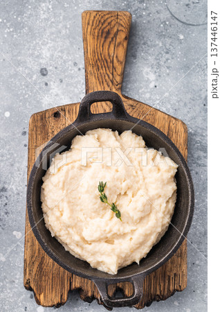 Overhead shot of a white savory condiment (aioli or horseradish) with a spoon on a rustic wooden board and concrete surface. Overhead shot of a white savory condiment (aioli or horseradish) with a spoon on a rustic wooden board and concrete surface. 137446147