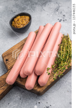 Raw hot dog sausages (frankfurters/wieners) on a cutting board with thyme and mustard on a rustic background. Food preparation concept. 137446155