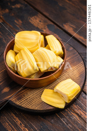 Sweet, golden jackfruit pods (bulbs) in a wooden bowl on a rustic dark wood table. Tropical fruit snack with copy space. Sweet, golden jackfruit pods (bulbs) in a wooden bowl on a rustic dark wood table. Tropical fruit snack with copy space. 137446161
