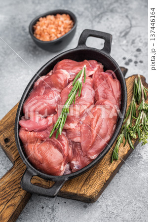 Raw quail breast fillets with rosemary and pink salt in a cast iron pan on a wooden board. Rustic gourmet food preparation. Raw quail breast fillets with rosemary and pink salt in a cast iron pan on a wooden board. Rustic gourmet food preparation. 137446164