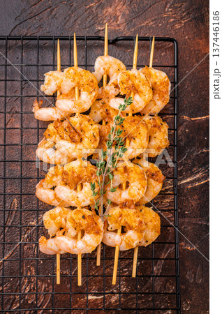 Appetizing BBQ shrimp prawn kebab seasoned with herbs and spices. Ready-to-eat grilled seafood on a wooden stick against a dark backdrop. Appetizing BBQ shrimp prawn kebab seasoned with herbs and spices. Ready-to-eat grilled seafood on a wooden stick against a dark backdrop. 137446186