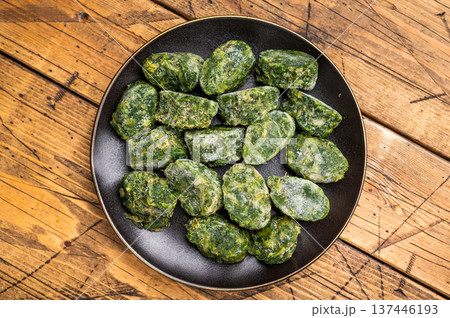 Raw, nutritious frozen spinach blocks on a dark plate, ready for thawing and cooking. Traditional rustic food photography. Raw, nutritious frozen spinach blocks on a dark plate, ready for thawing and cooking. Traditional rustic food photography. 137446193