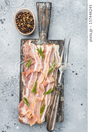 Raw streaky bacon pork slices with rosemary on rustic board perfect for cooking themes recipe visuals and gourmet food 137446245