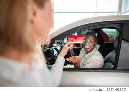 Woman receiving new car key at dealership Woman receiving new car key at dealership 137446337