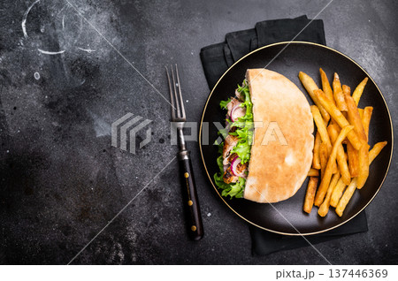 Turkish Shawarma, Doner kebab with grilled chicken meat in pita bread on a plate with french fry. black background. top view 137446369
