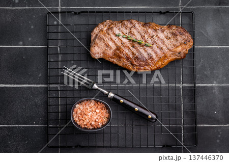 Grilled Striploin steak, New York strip beef meat steak on a rack. black background. top view Grilled Striploin steak, New York strip beef meat steak on a rack. black background. top view 137446370