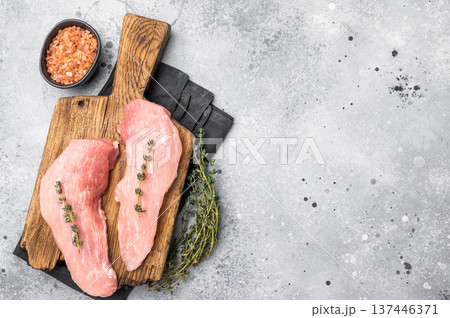 Ready for cooking pork loin fillets, raw tenderloin meat on a wooden board. Gray background. top view 137446371