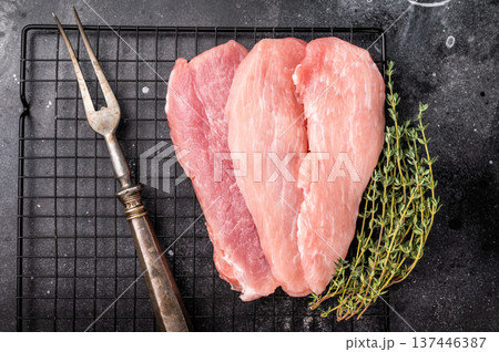 Raw pork fillet meat for schnitzel, steaks on a rack. black background. top view 137446387