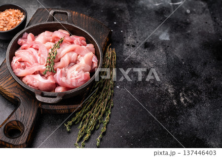 Raw Chicken sliced thighs fillets in a skillet. black background. top view 137446403