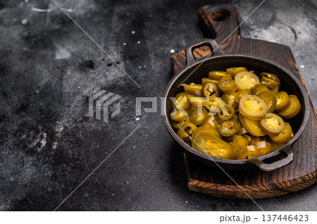 Pickled Jalapeno, Marinated Green Mexican pepper Slices in a skillet. black background. top view Pickled Jalapeno, Marinated Green Mexican pepper Slices in a skillet. black background. top view 137446423
