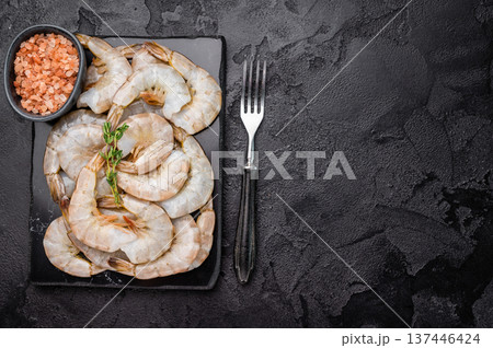 Raw headless white shrimps prawns on a marble board. Top view. Black background Raw headless white shrimps prawns on a marble board. Top view. Black background 137446424