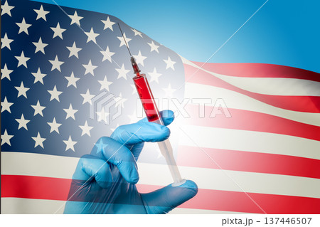 Hand holds syringe against waving American flag 137446507