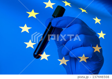 Gloved hand holds test tube against EU flag backdrop Gloved hand holds test tube against EU flag backdrop 137446508