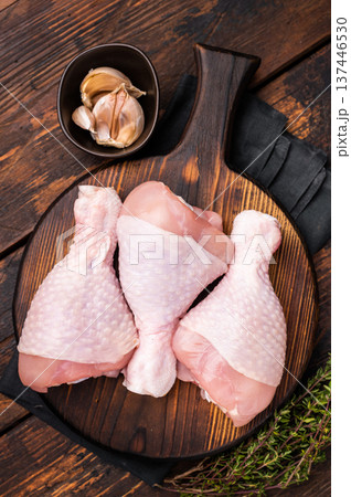 Uncooked poultry drumsticks, raw chicken legs ideal for your favorite recipes, waiting to be seasoned and cooked to perfection. wooden background. top view Uncooked poultry drumsticks, raw chicken legs ideal for your favorite recipes, waiting to be seasoned and cooked to perfection. wooden background. top view 137446530