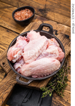 Juicy uncooked chicken wings, a versatile ingredient perfect for frying, baking, or grilling to perfection. wooden background. top view 137446542
