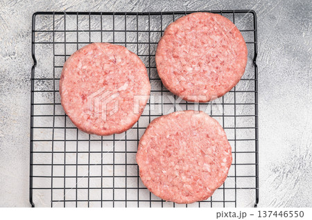 Close up of a juicy raw meat patty cutlet, ideal for crafting mouthwatering sandwiches and savory dishes. white background. top view 137446550