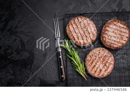 Juicy grilled meat patty cutlet with perfect grill marks, ideal for mouthwatering burgers and summer barbecues. black background. top view 137446586