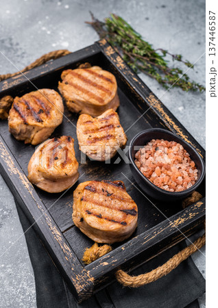 Tender char grilled pork medallion steak, perfect for adding a touch of elegance to your dinner plate.grey background. top view Tender char grilled pork medallion steak, perfect for adding a touch of elegance to your dinner plate.grey background. top view 137446587