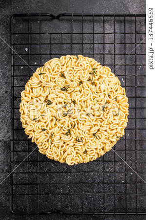 Raw instant ramen noodles, perfectly twisted and ready to be boiled for a delicious homemade soup. black background. top view Raw instant ramen noodles, perfectly twisted and ready to be boiled for a delicious homemade soup. black background. top view 137446589