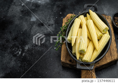 Raw baby corn maize arranged in black skillet top view with thyme on rustic board perfect for asian cuisine and cooking concepts Raw baby corn maize arranged in black skillet top view with thyme on rustic board perfect for asian cuisine and cooking concepts 137446611