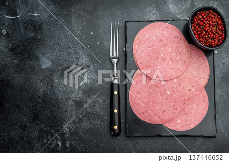 Thin round slices of Turkish beef salam arranged on a slate board with red pepper on dark stone background ideal for deli and food stock use 137446652