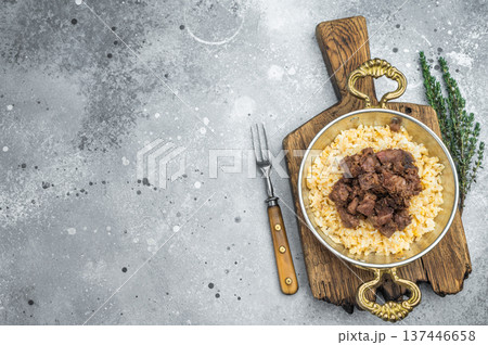 Kawurma qawurma layered over aromatic rice pilaf, highlighting seared protein fibers, granular structure and vintage culinary setup. 137446658