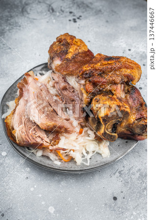 Crispy roasted pork knuckle with sliced tender shank meat served on sauerkraut over gray stone background with mustard and fork styling. Crispy roasted pork knuckle with sliced tender shank meat served on sauerkraut over gray stone background with mustard and fork styling. 137446667