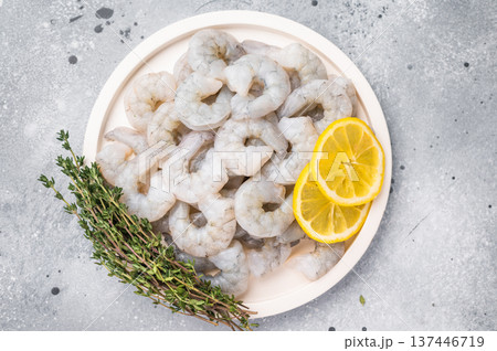 Fresh prawn shrimp tails on a wooden board. Gourmet ingredient with spices and lemon slices, ready for cooking on a rustic table. 137446719