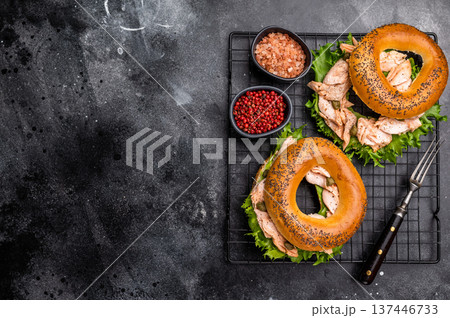 Bagel sandwich with lox, smoked salmon, lettuce and cream cheese on a rack. black background. top view Bagel sandwich with lox, smoked salmon, lettuce and cream cheese on a rack. black background. top view 137446733