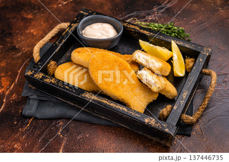 Crusted Fish sticks fingers with lemon and tartar sauce in wooden tray. brown background. top view Crusted Fish sticks fingers with lemon and tartar sauce in wooden tray. brown background. top view 137446735