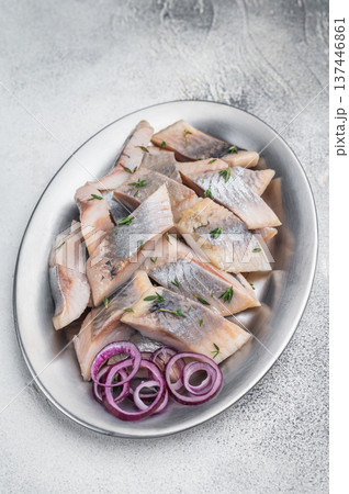 Salted and marinated herring pieces with red onion and thyme served in white dish on wooden board. Light stone background with copy space. Salted and marinated herring pieces with red onion and thyme served in white dish on wooden board. Light stone background with copy space. 137446861