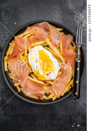 Traditional huevos rotos dish with sunny egg yolk fried potatoes and jamon served in plate rustic style 137446874