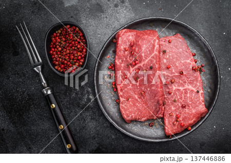 Fresh raw flatiron chuck beef steak with rich marbling on dark ceramic plate overhead view premium flatiron chuck cut for gourmet cooking 137446886