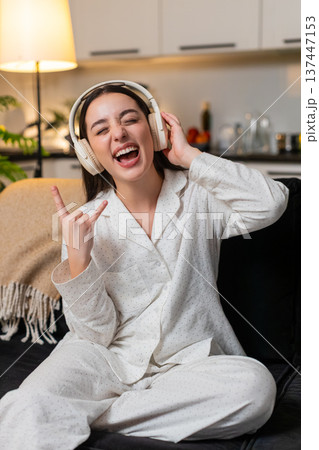 Young woman hears song in headphones starts seated dance rock moves laughs cheers yeah energy wild Young woman hears song in headphones starts seated dance rock moves laughs cheers yeah energy wild 137447153