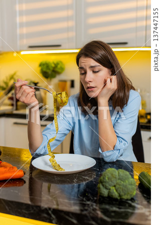 Young woman disappointed checking measuring tape during diet struggle weight loss at home in kitchen 137447155