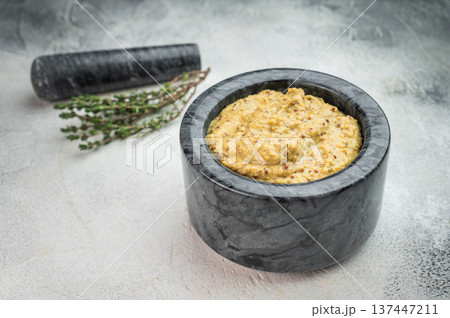 Traditional German Bavarian mustard sweet and mild prepared in stone mortar overhead view on light textured background Traditional German Bavarian mustard sweet and mild prepared in stone mortar overhead view on light textured background 137447211