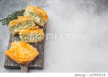 Traditional spanakopita made with phyllo pastry, spinach and cheese filling, sliced baked appetizer on white background Traditional spanakopita made with phyllo pastry, spinach and cheese filling, sliced baked appetizer on white background 137447214