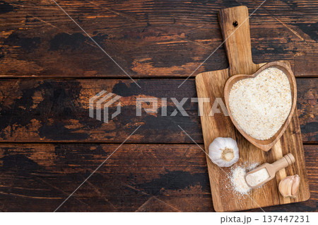 Granulated dried garlic spice in heart shaped wooden bowl on rustic board. Natural seasoning flatlay with copy space Granulated dried garlic spice in heart shaped wooden bowl on rustic board. Natural seasoning flatlay with copy space 137447231
