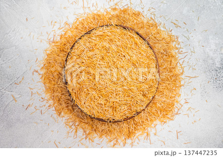 Kadaif pastry dough with fine crispy strands in wooden bowl. Baking ingredient flatlay on dark concrete background 137447235