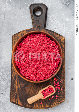 Sublimated raspberry granules with bright red color in wooden bowl. Natural berry texture with copy space flatlay. 137447252