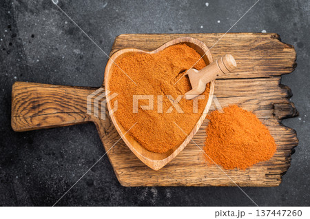 Paprika spice powder with rich orange red color in heart bowl. Aromatic seasoning ingredient flatlay with copy space 137447260