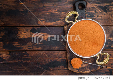 Ground paprika powder in metal bowl with spoon on rustic wooden board. Vibrant red spice flatlay with copy space Ground paprika powder in metal bowl with spoon on rustic wooden board. Vibrant red spice flatlay with copy space 137447261