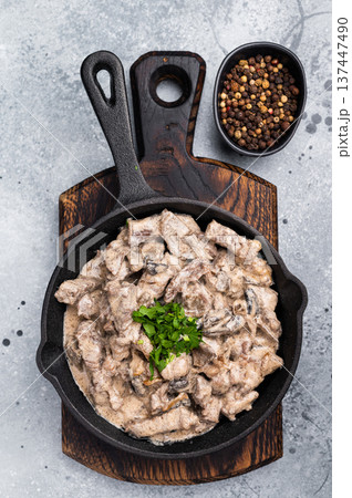Creamy beef stroganoff with fresh greenery, savory mushroom sauce and caramelized onions in a skillet. grey background. top view 137447490